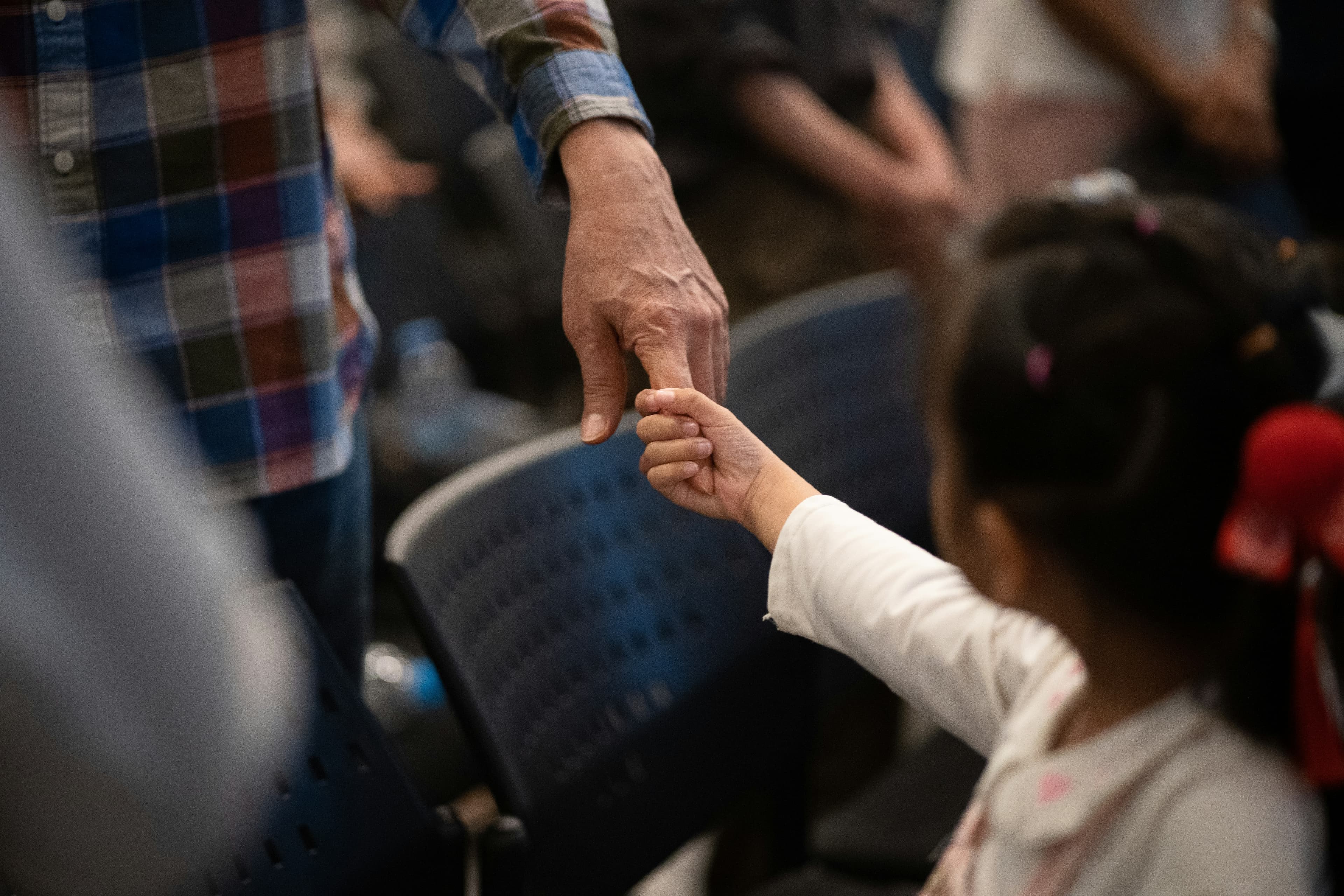 An adult and a child holding hands, the child's hand wrapped around the adult's finger.